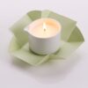 Candela da massaggio all'arnica ed erbe alpine Vivalu accesa, con confezione aperta e fiamma ardente.