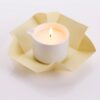 Candela da massaggio alla vaniglia Vivalu accesa, con confezione aperta color crema e fiamma ardente.