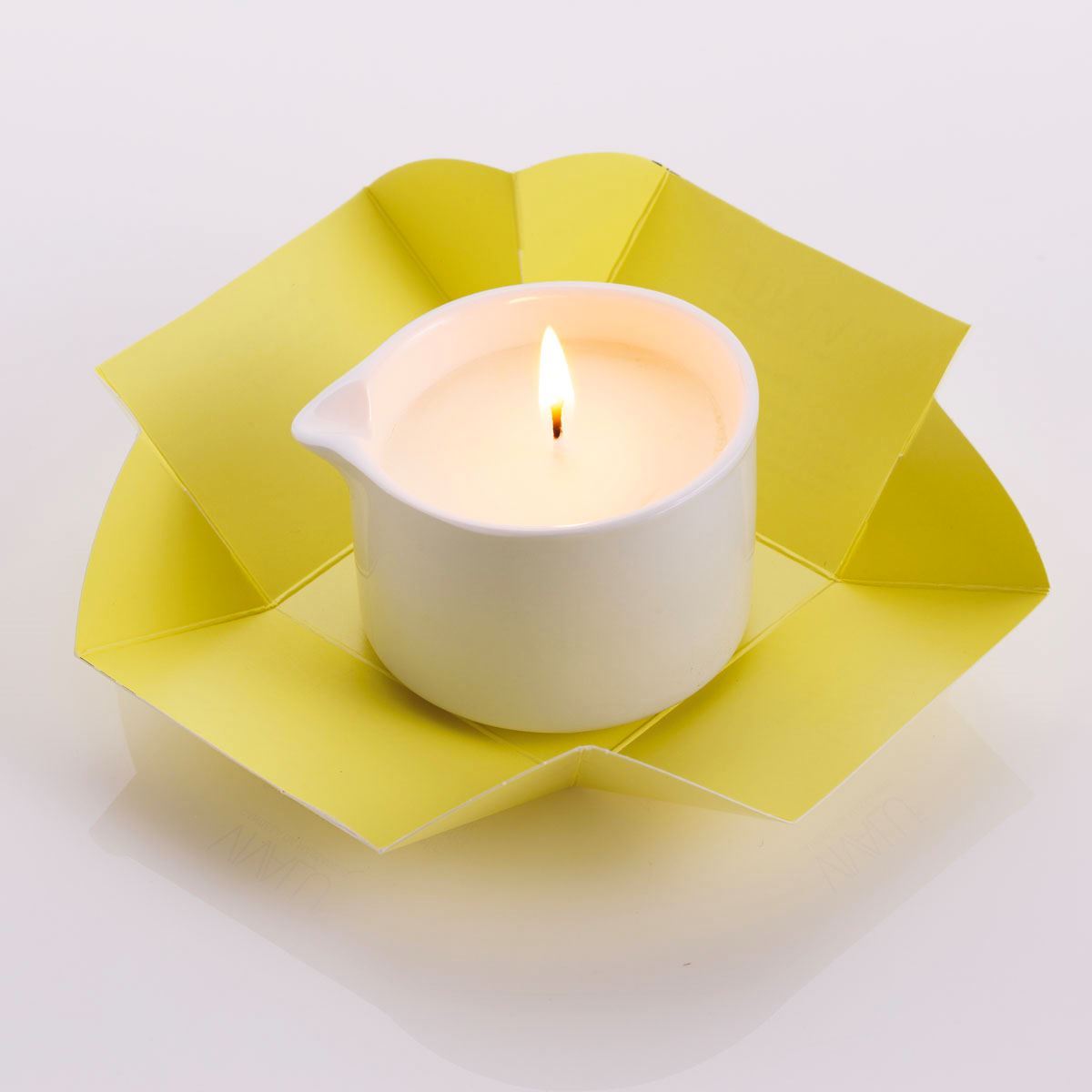 Candela da massaggio ai vinaccioli d'uva Vivalu accesa, con confezione aperta gialla e fiamma ardente.